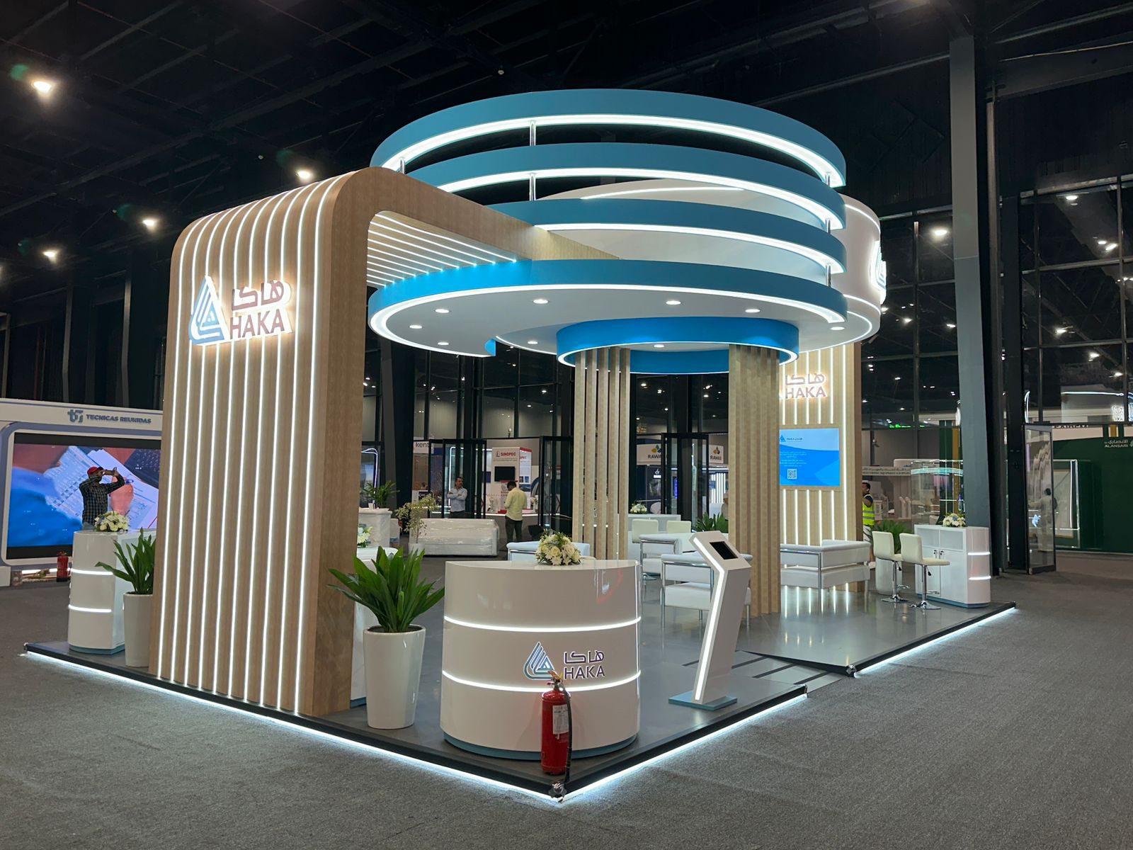 Modern exhibition booth with branded display panels and lighting at busy trade show event